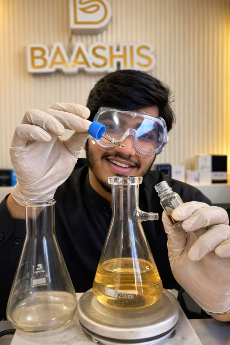 Person in a lab setting with beakers and goggles, wearing gloves, in front of a 'BAASHIS' branded background.